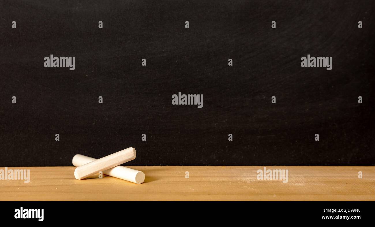 School chalkboard, blank empty black board and white chalk piece on wooden frame sill, copy space Stock Photo