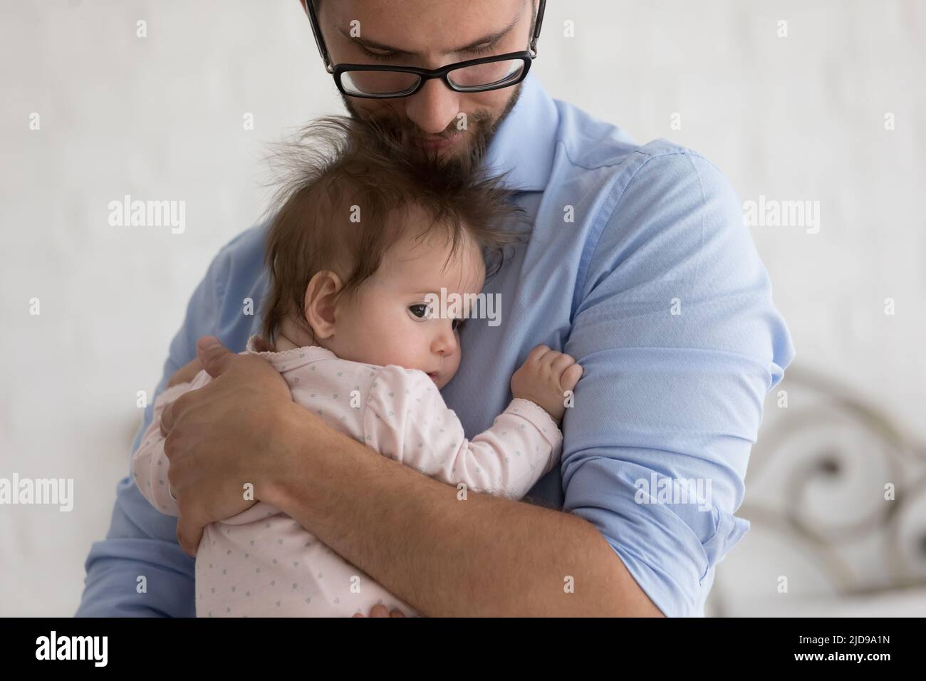 Caring father holds on arms, calming his cute baby Stock Photo