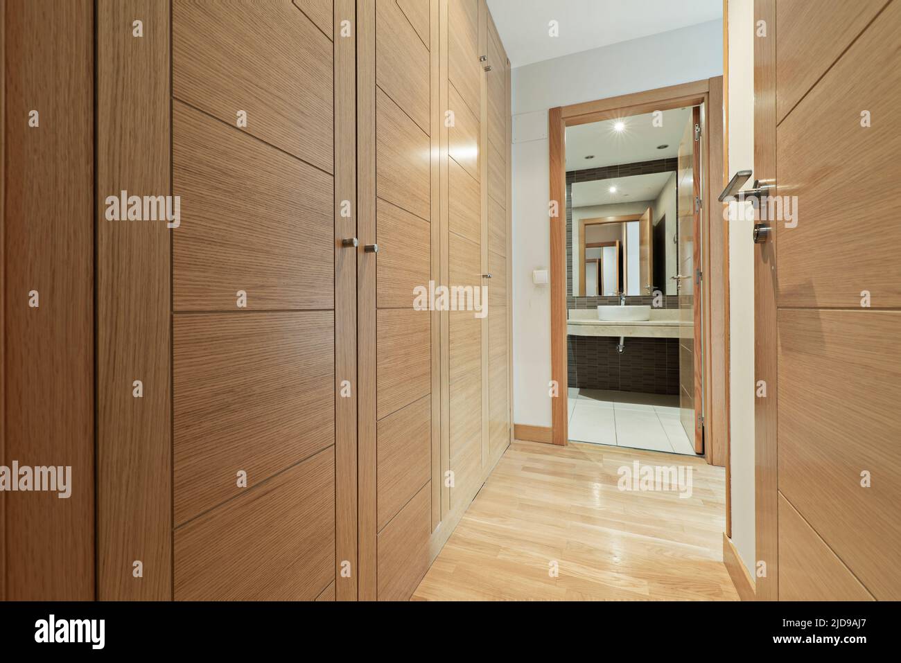 Dressing room with oak wood doors with access to en-suite bathroom with cream marble top Stock Photo