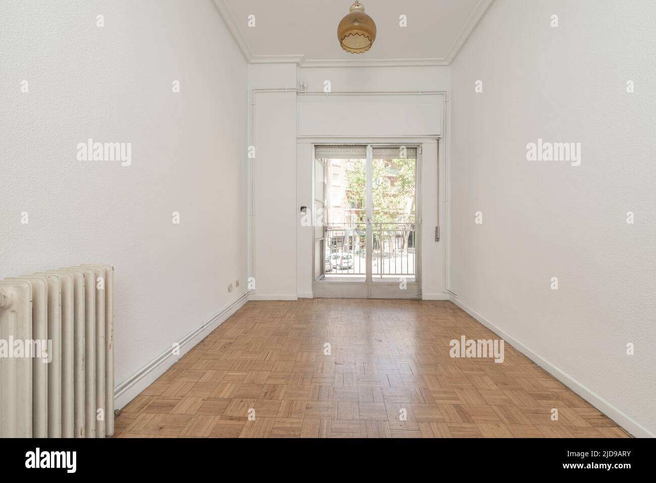 Empty living room with oak parquet and exit to a terrace through an aluminum window with sliding leaves Stock Photo