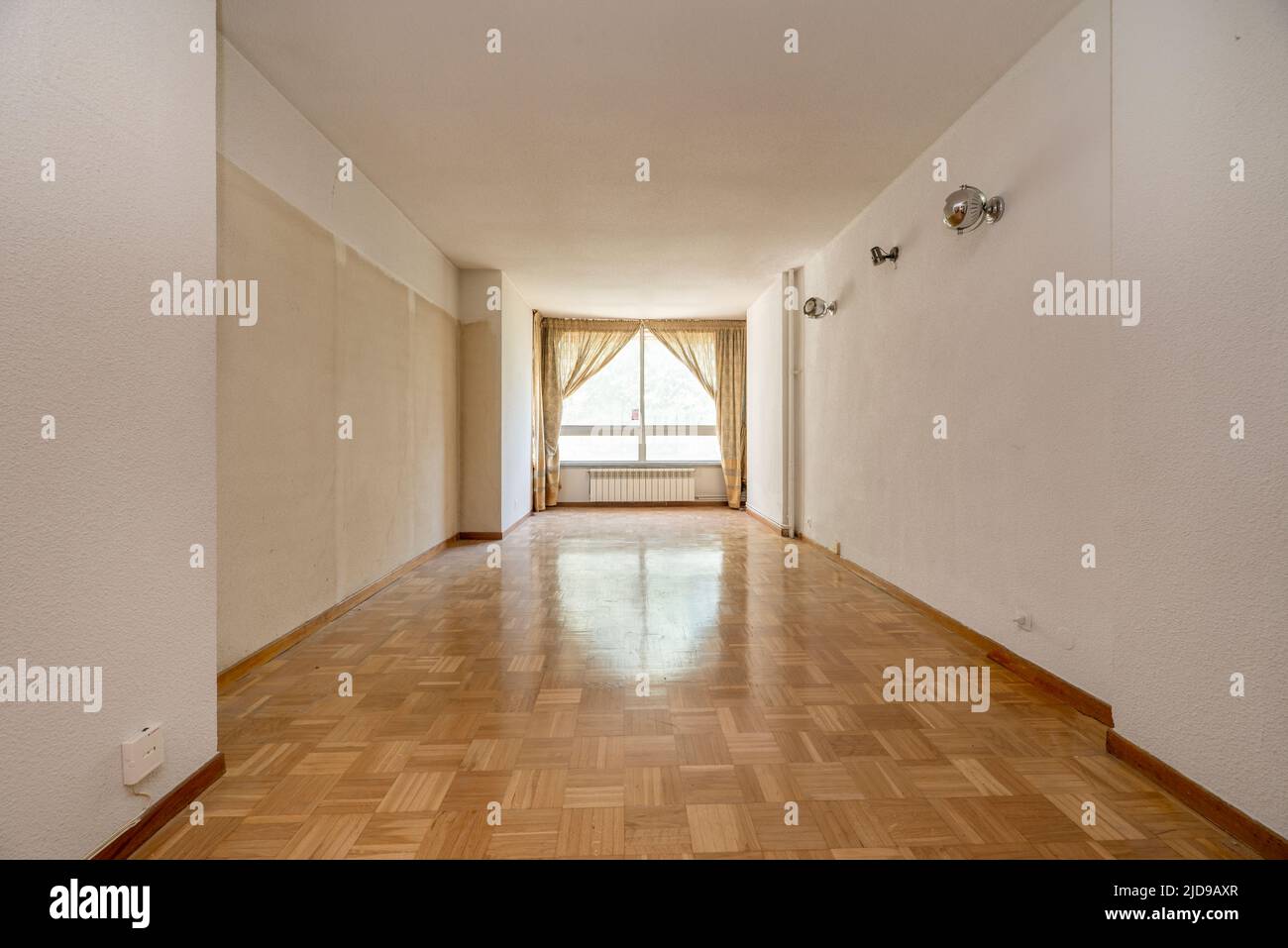 Empty living room with glossy parquet flooring, curtained window and white walls Stock Photo