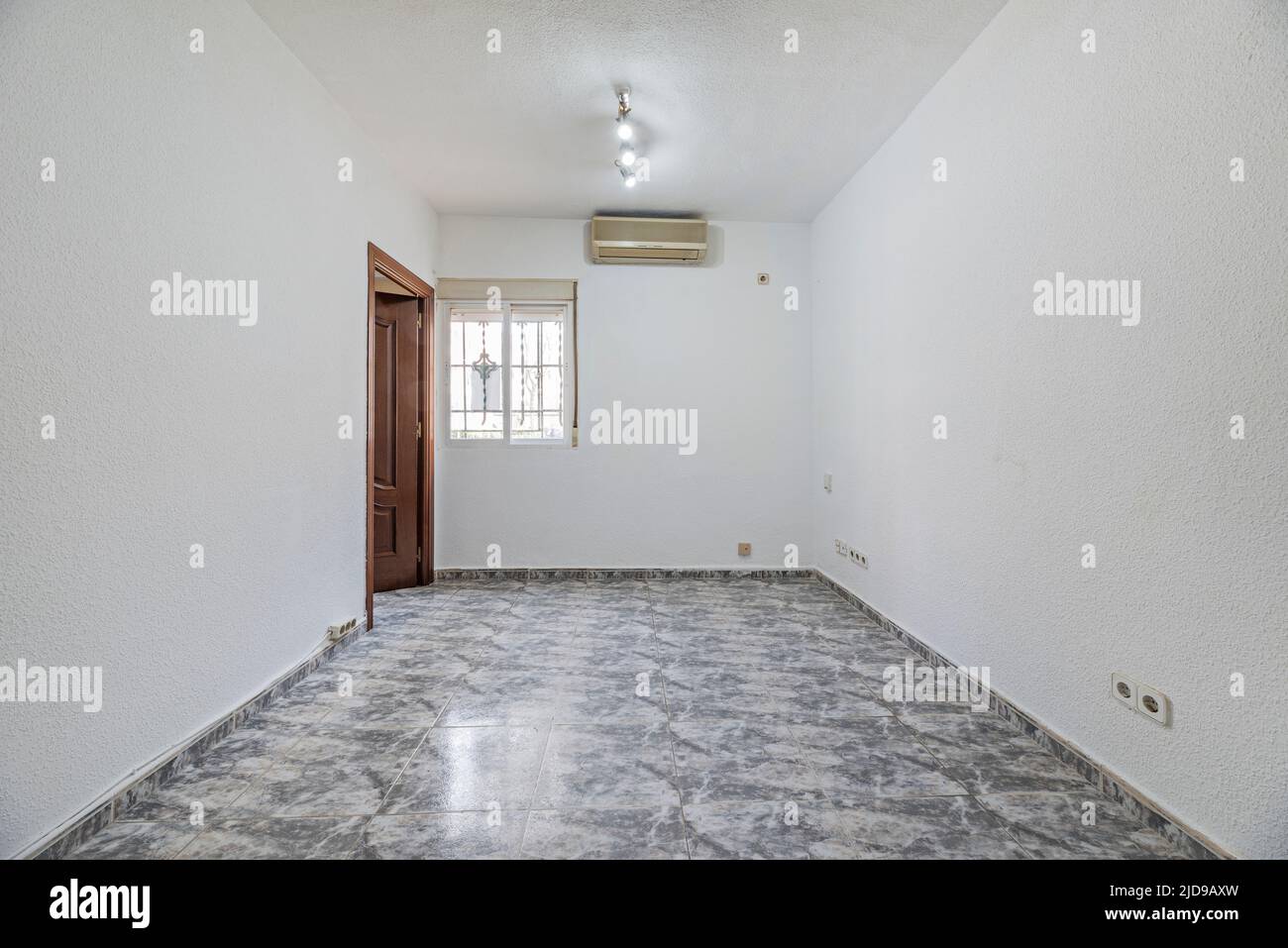 Empty living room with white and gray stoneware floors, wooden carpentry and air conditioning unit Stock Photo
