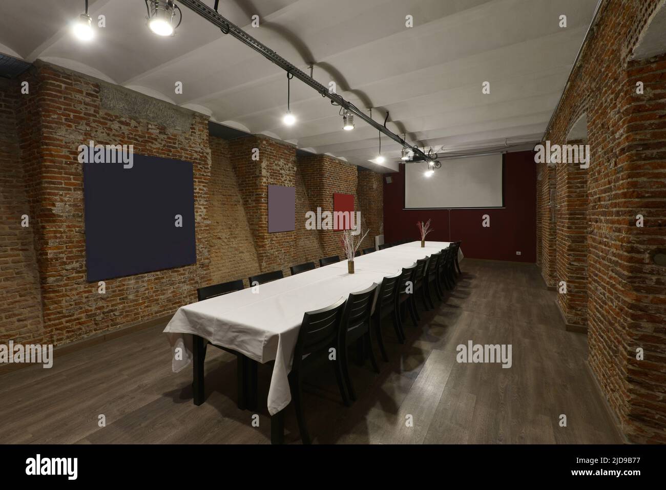 Elongated dining table in a restaurant with a basement and exposed brick walls with vaulted ceilings Stock Photo