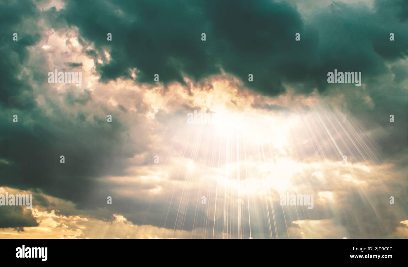 Sun beams shining through dark clouds on sky nature background Stock Photo