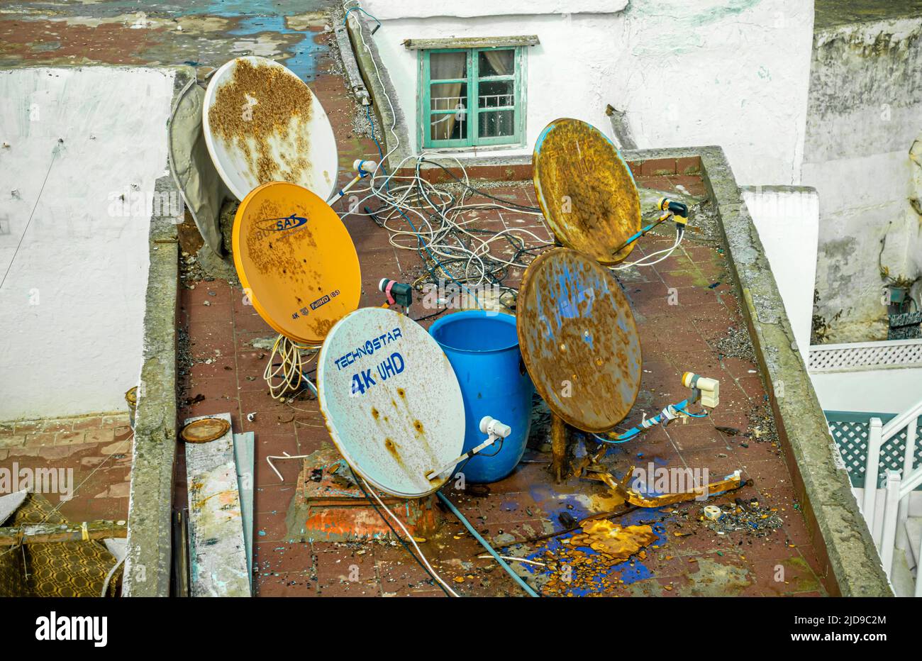 Several rusty dish-shaped satellite parabolic antennas and 4k UHD dish antenna o na roof of a house in central Essaouira, Morocco Stock Photo