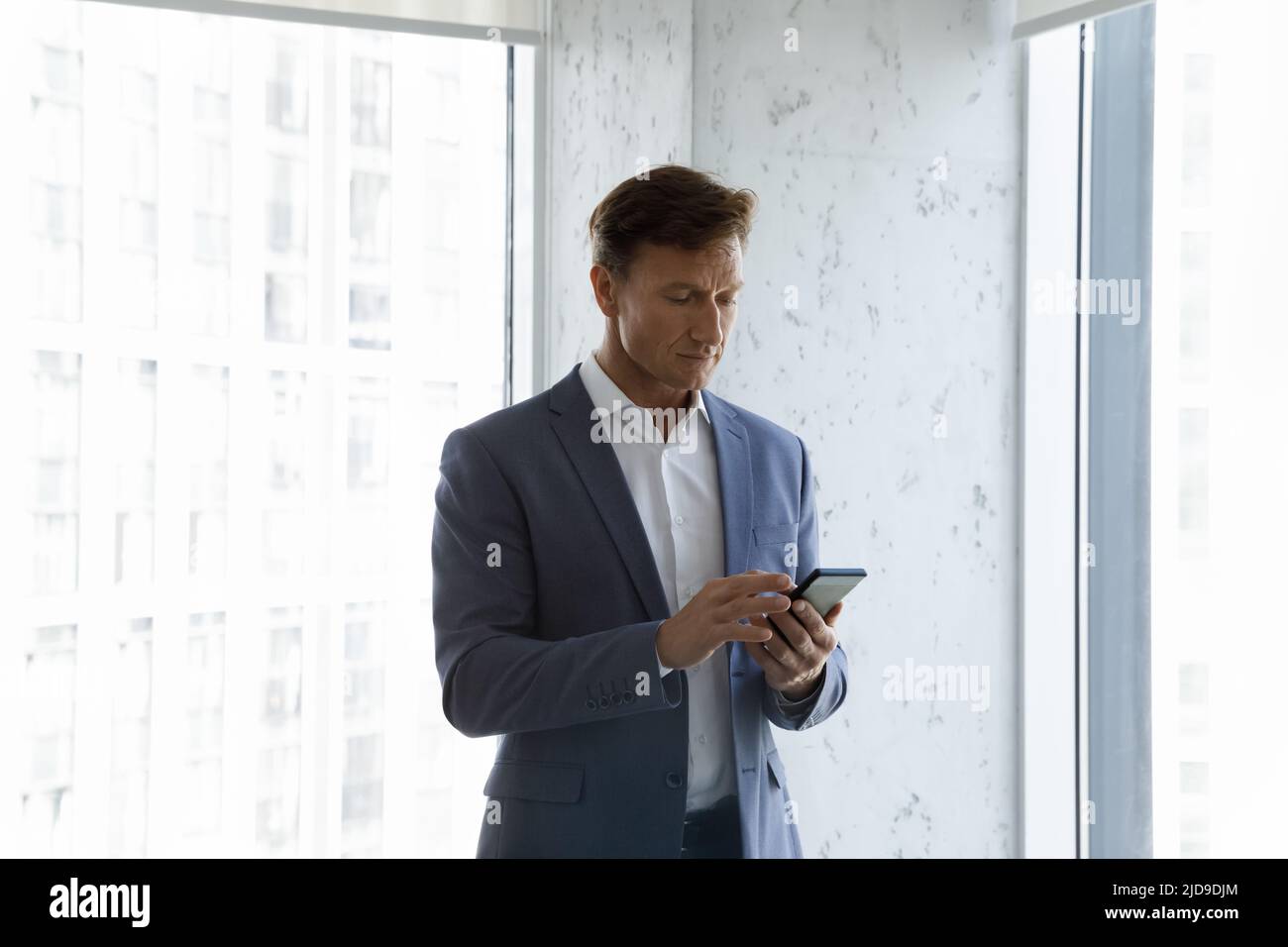 Serious middle-aged office employee make call use modern smartphone Stock Photo