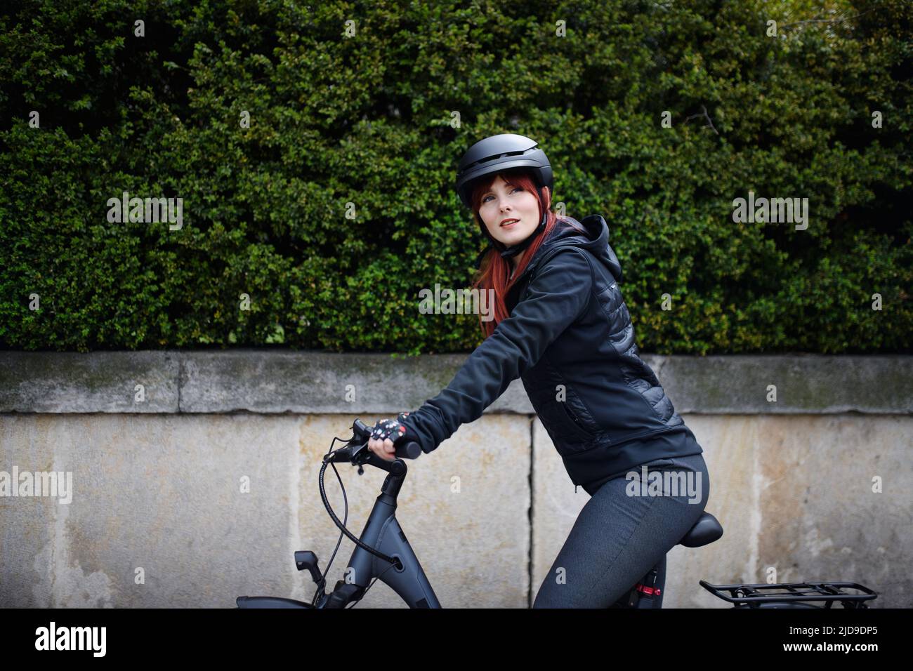 Portrait of businesswoman commuter on the way to work with bike looking at camera, sustainable lifestyle concept. Stock Photo
