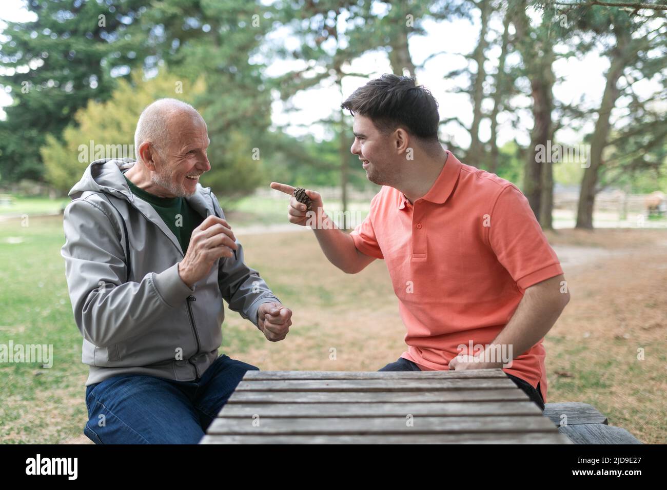 Happy senior father with his adult son with Down syndrome playing and sitting in park. Stock Photo