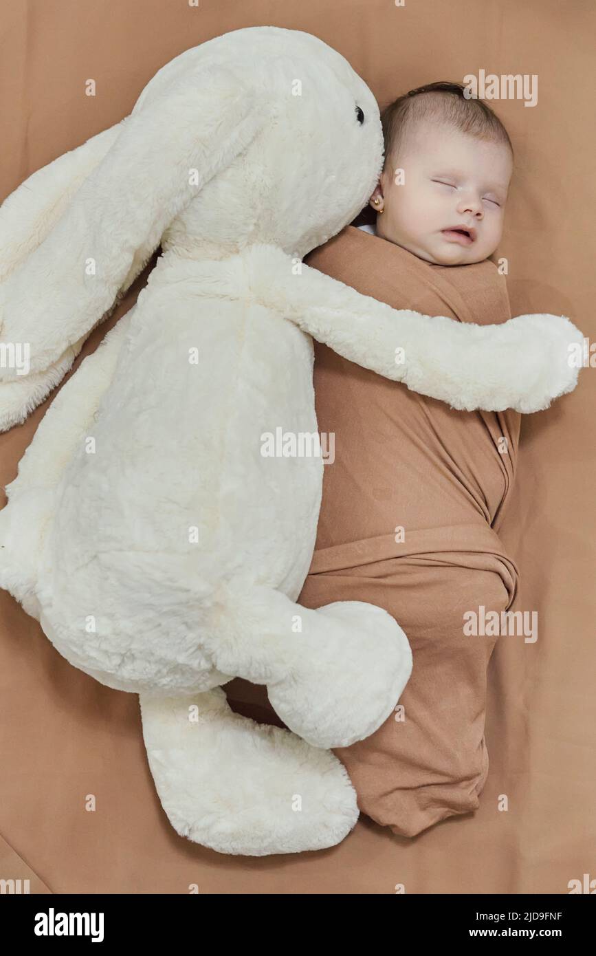 Newborn baby with her white bunny toy. Cute mixed race baby girl sleeping in the bed Stock Photo