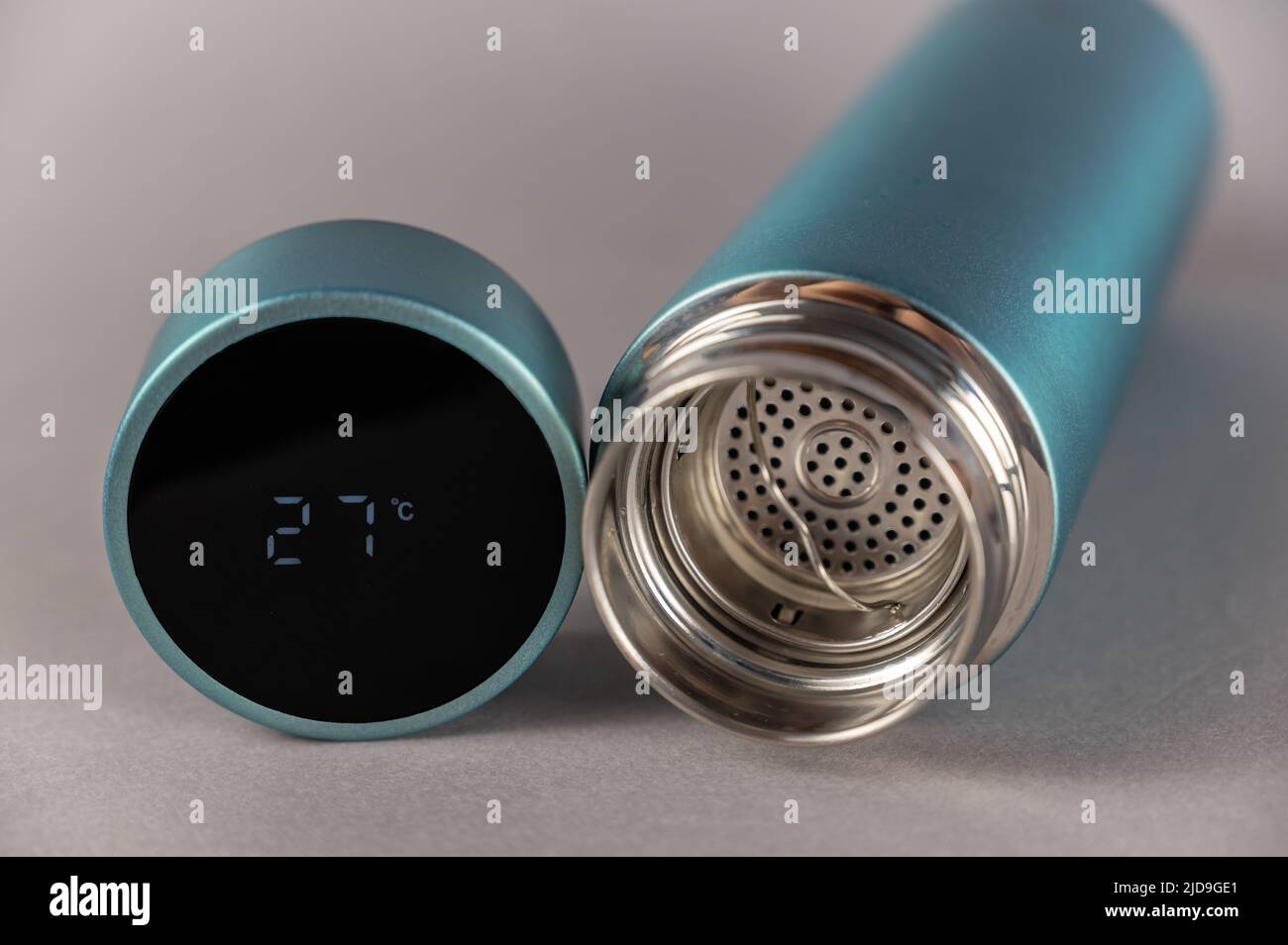 Thermos with open lid on gray background. Cylindrical lid with LED