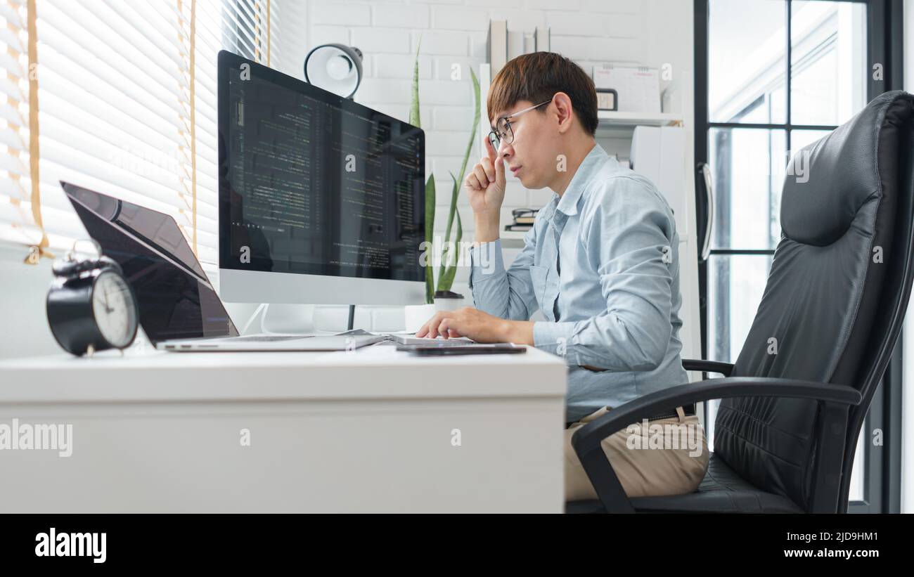 Software development concept, Male programmer looking data on laptop and typing codes on keyboard. Stock Photo