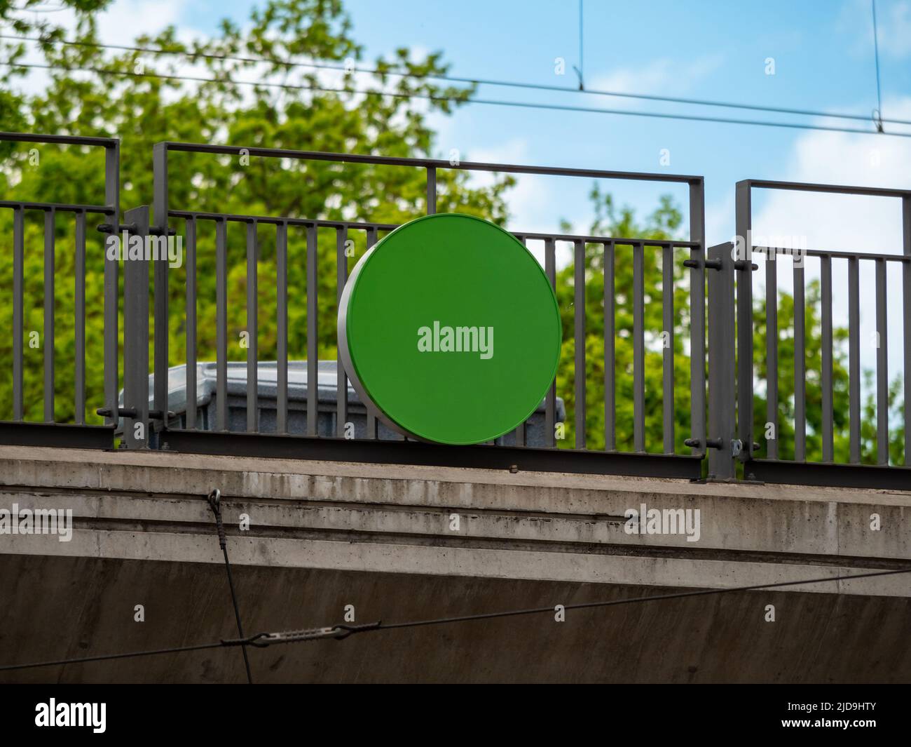 Empty green sign on a railing in Germany. The blank round plate is mounted to a bridge that everybody can see from distance. This is a template. Stock Photo