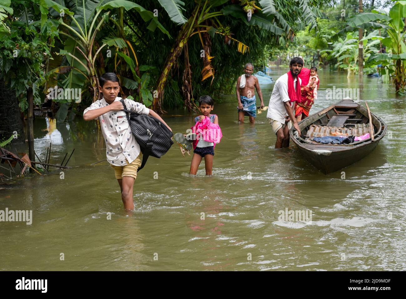Flood affected people coming towards a safer place with belongings, at a village on June 17, 2022 in Barpeta, India. Assam flood situation deteriorates due to heavy rain, over a million people affected. Stock Photo