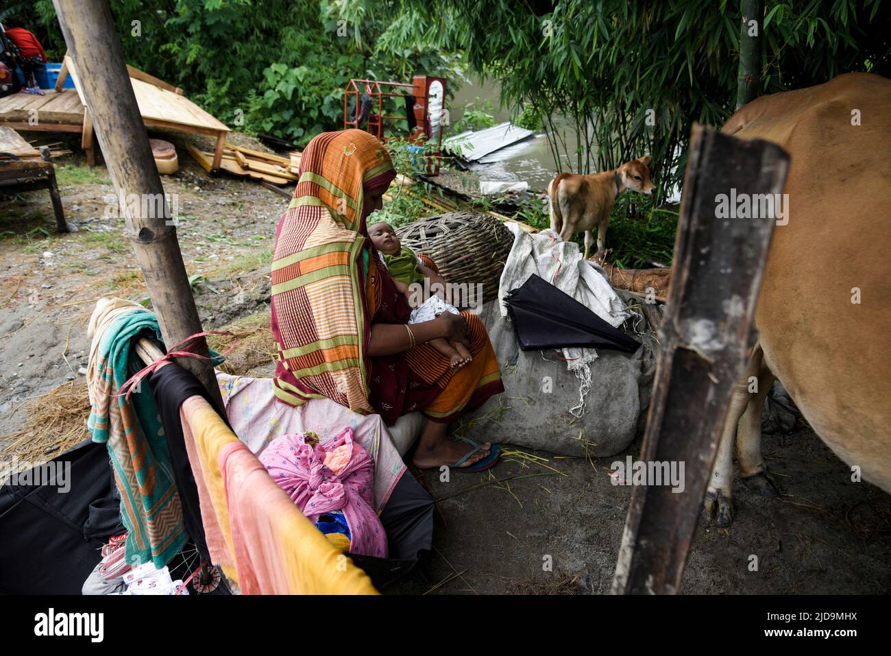 Flood affected woman with her child sitting in a makeshift shelter, at a village on June 17, 2022 in Barpeta, India. Assam flood situation deteriorates due to heavy rain, over a million people affected. Stock Photo