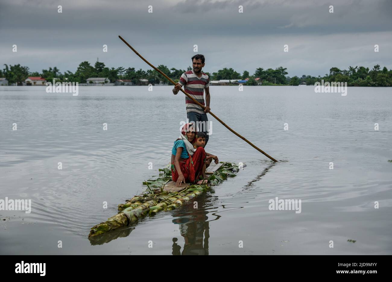 Flood affected people travel on a banana raft as they are going to a makeshift shelter, at a village on June 17, 2022 in Barpeta, India. Assam flood situation deteriorates due to heavy rain, over a million people affected. Stock Photo