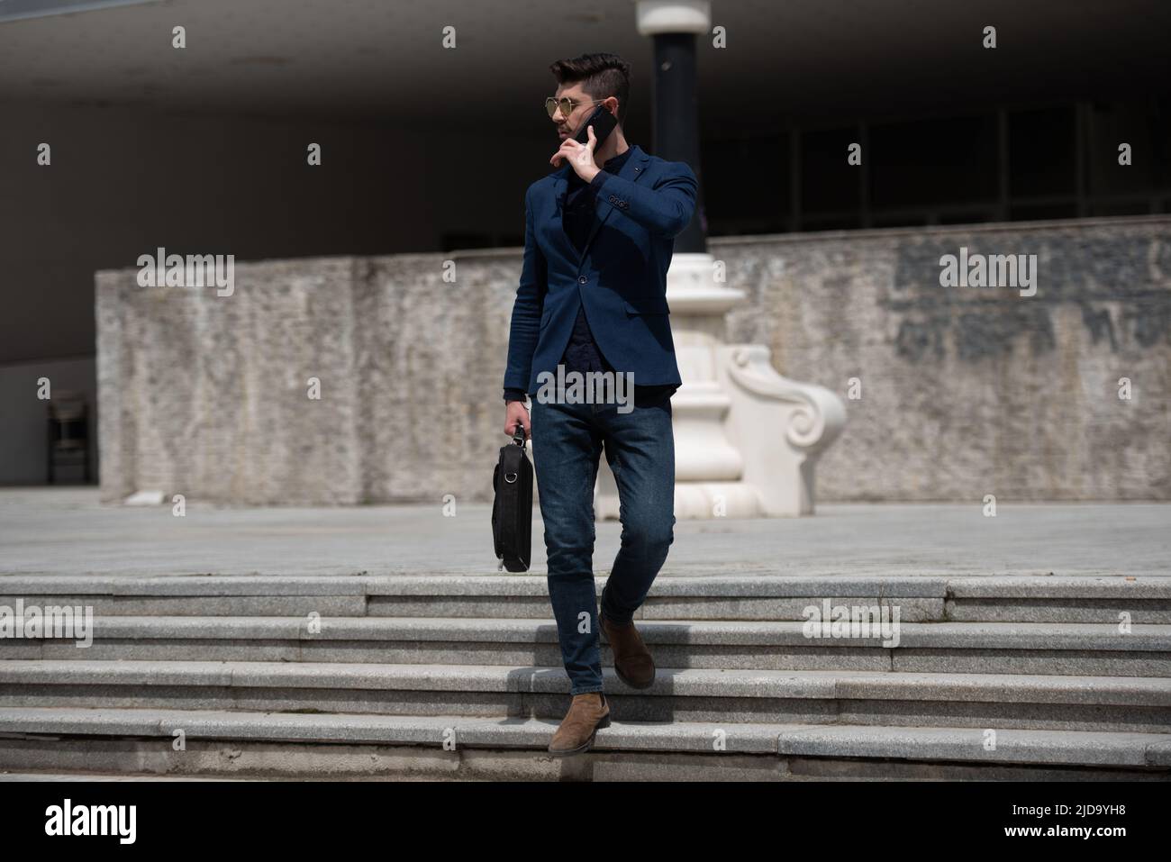 Urban businessman is going down the stairs while talking on the phone Stock Photo