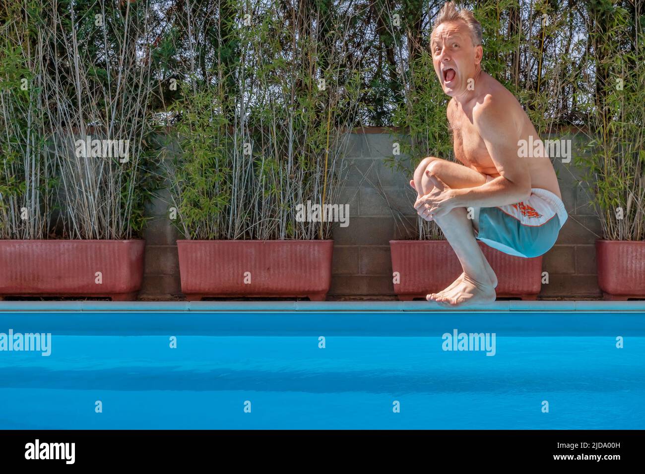 Middle aged white man diving into a swimming pool, cannonball style ...