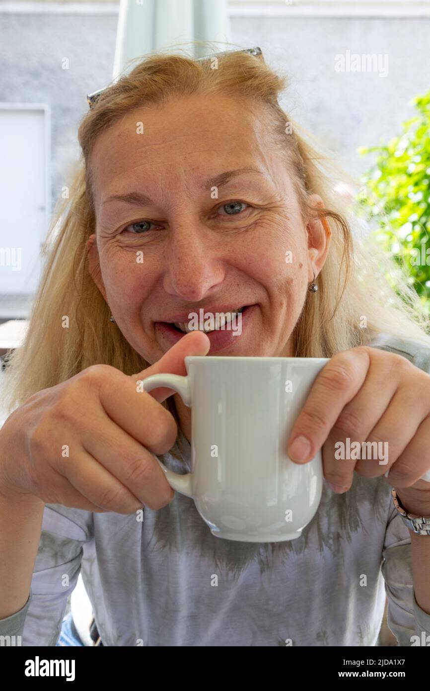 Older blond east European woman drinking tea Stock Photo