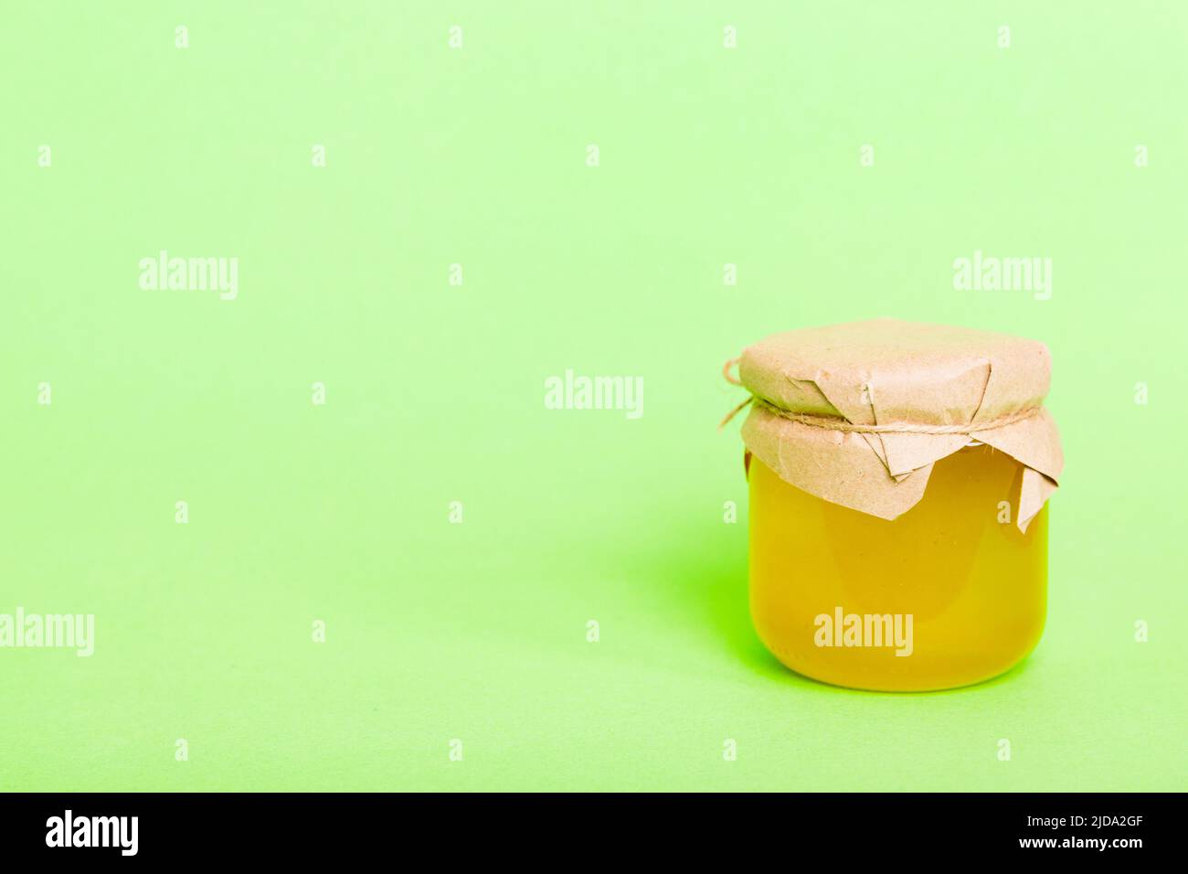 Glass jar full of honey on a colored background. Honey Bottle MockUp