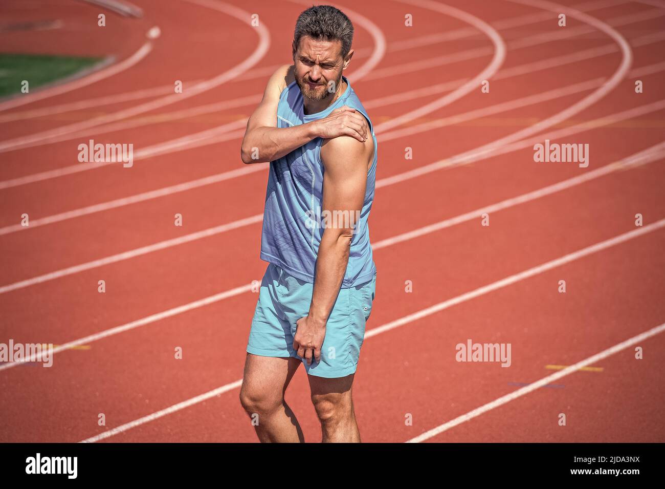 man has injury shoulder after exercise on stadium. fitness gym outdoor