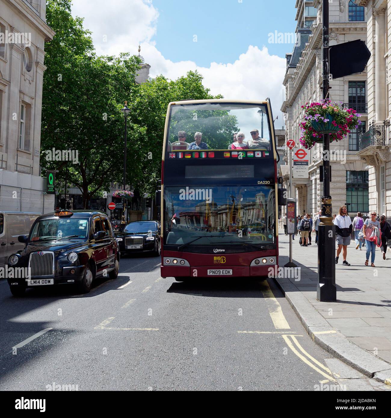 London, Greater London, England, June 08 2022: Tourists sitting on an Open top bus on a street with a taxi beside. Stock Photo