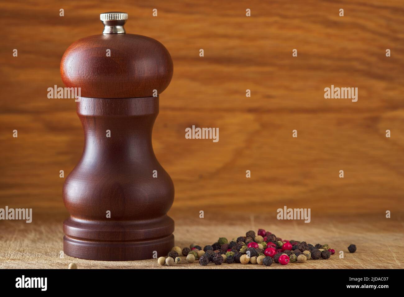 Wooden brown grinding salt and pepper shaker on wood with colored peppercorns and copy space Stock Photo