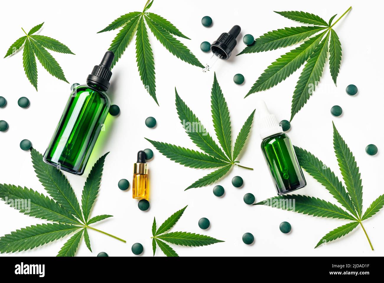 Top view of green hemp leaves with cosmetics glass reusable bottles. Medical and Recreational Use of Marijuana. Natural cosmetics or superfood Stock Photo