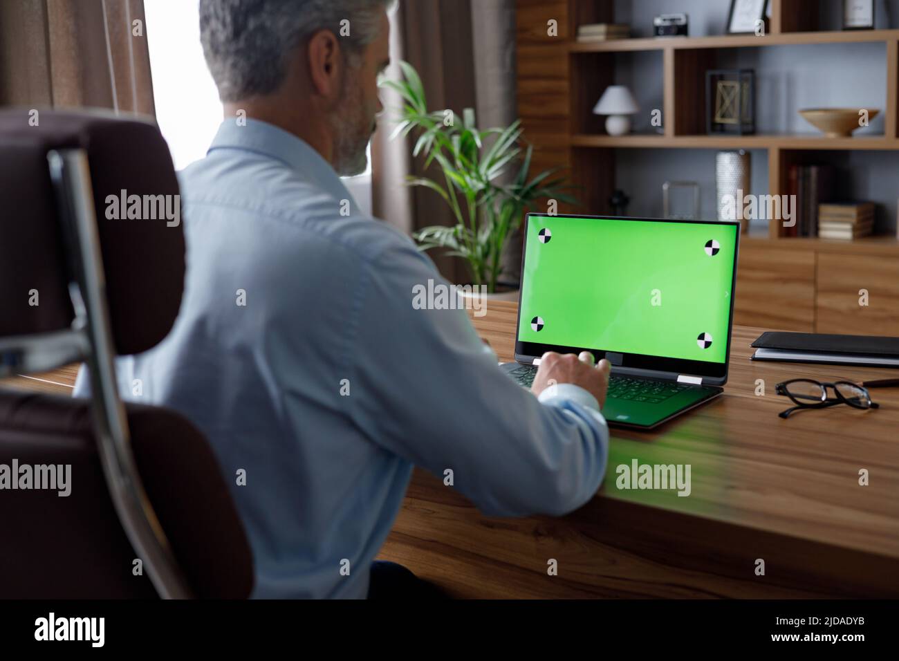 Businessman working with laptop green screen with tracking markers. Male worker talking and