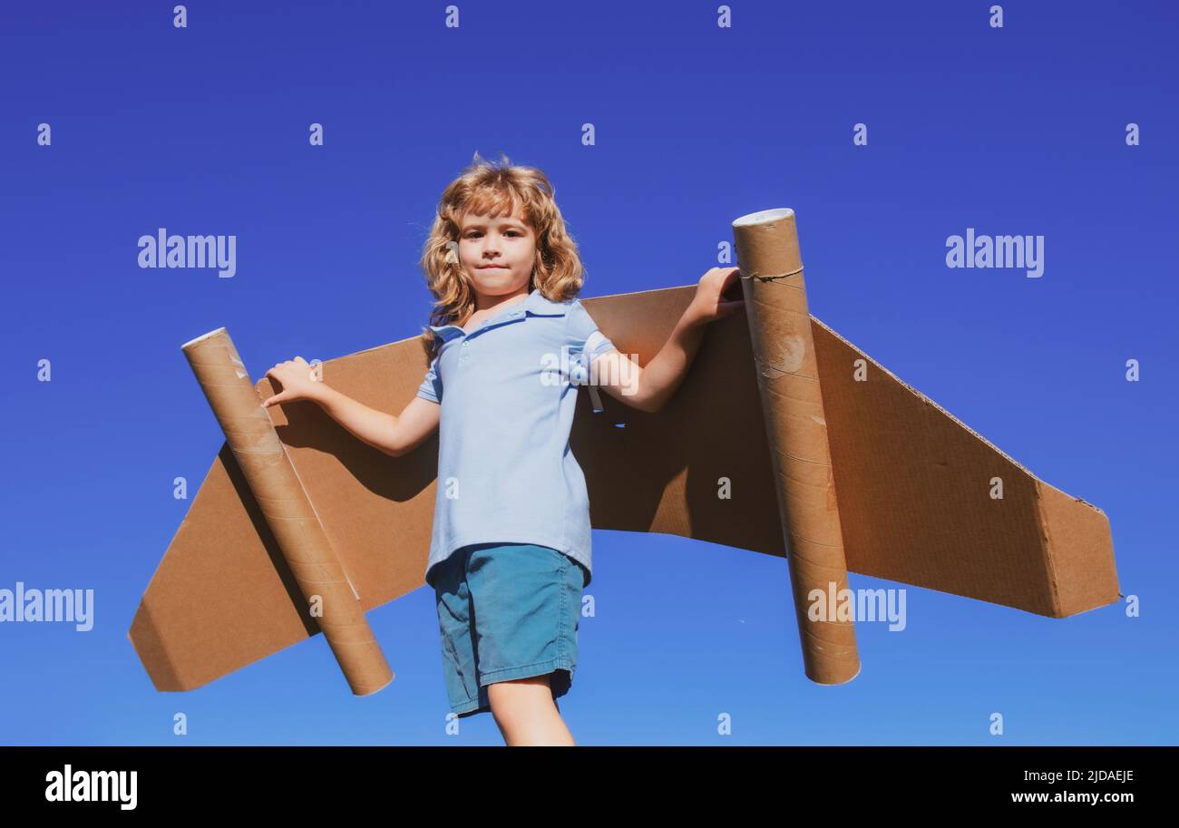 Happy child with paper wings against blue sky. Kid with toy jetpack ...