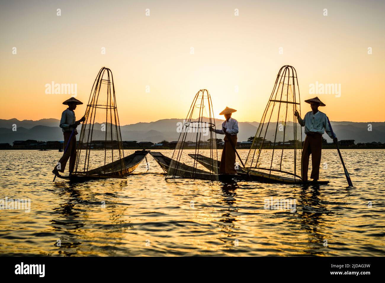 Three fishermen fishing on Lake Inles using traditional cone shape fishing nets. Stock Photo