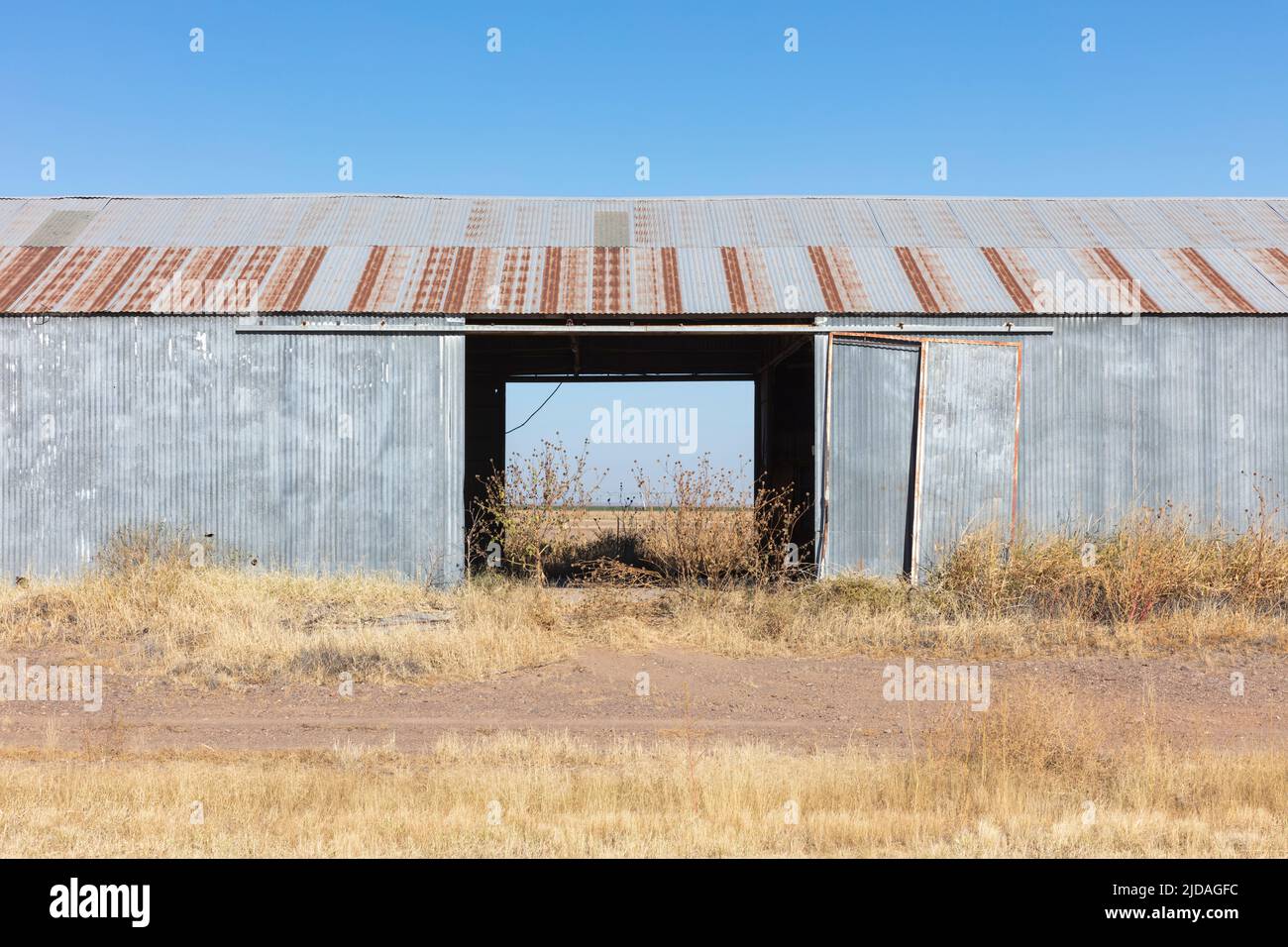 Abandoned rusting metal farm building with large open doors. Stock Photo