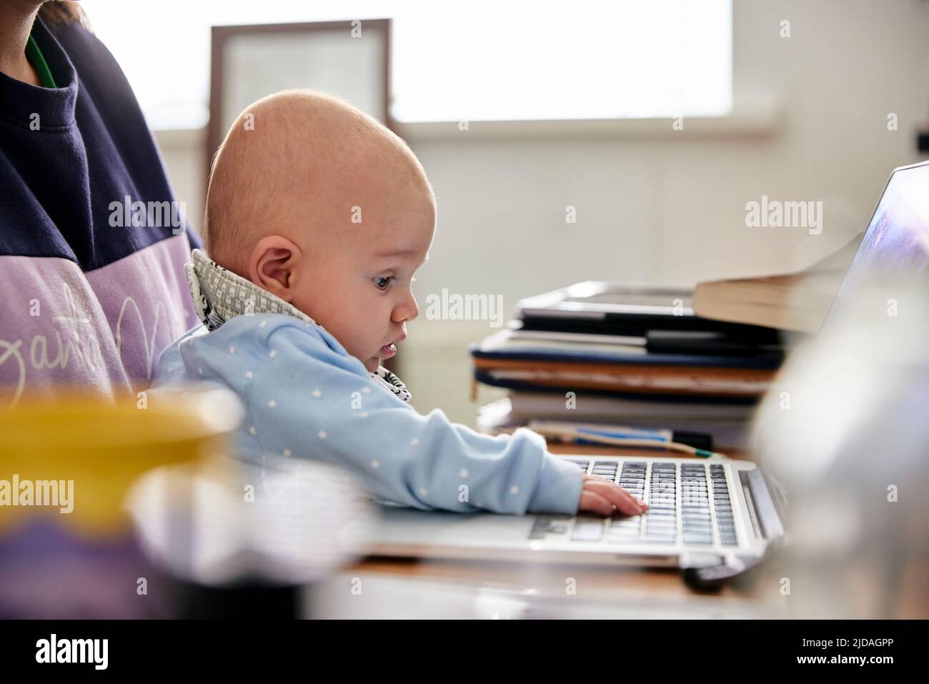 Baby boy touching computer keyboard sitting on mother's lap Stock Photo