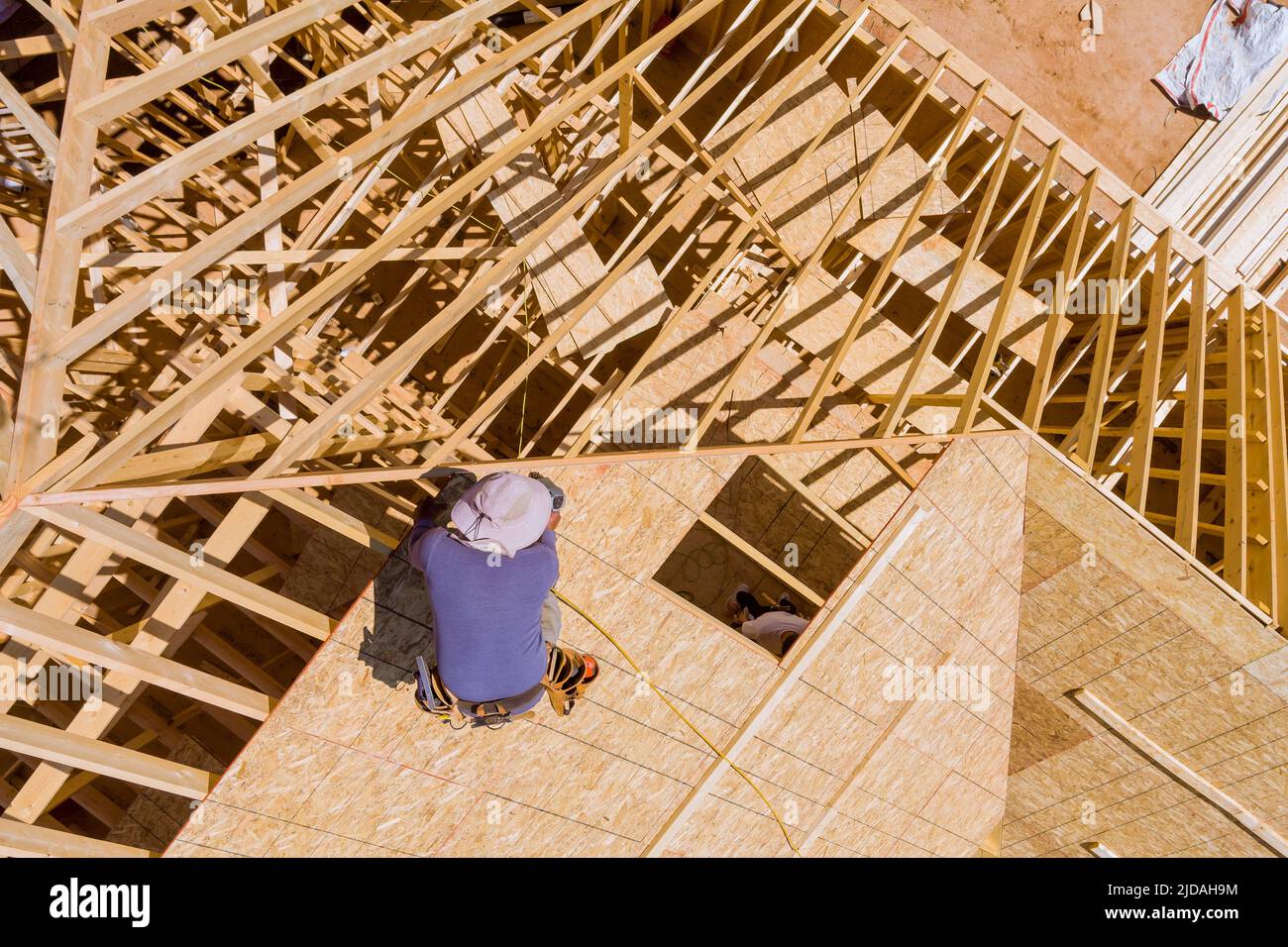 Construction working on the nailing plywood roof sheathing of a new