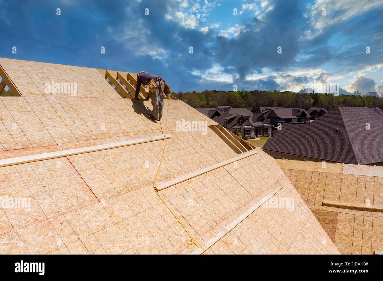 Workers build a roof on the house applying roof plywood panels Stock