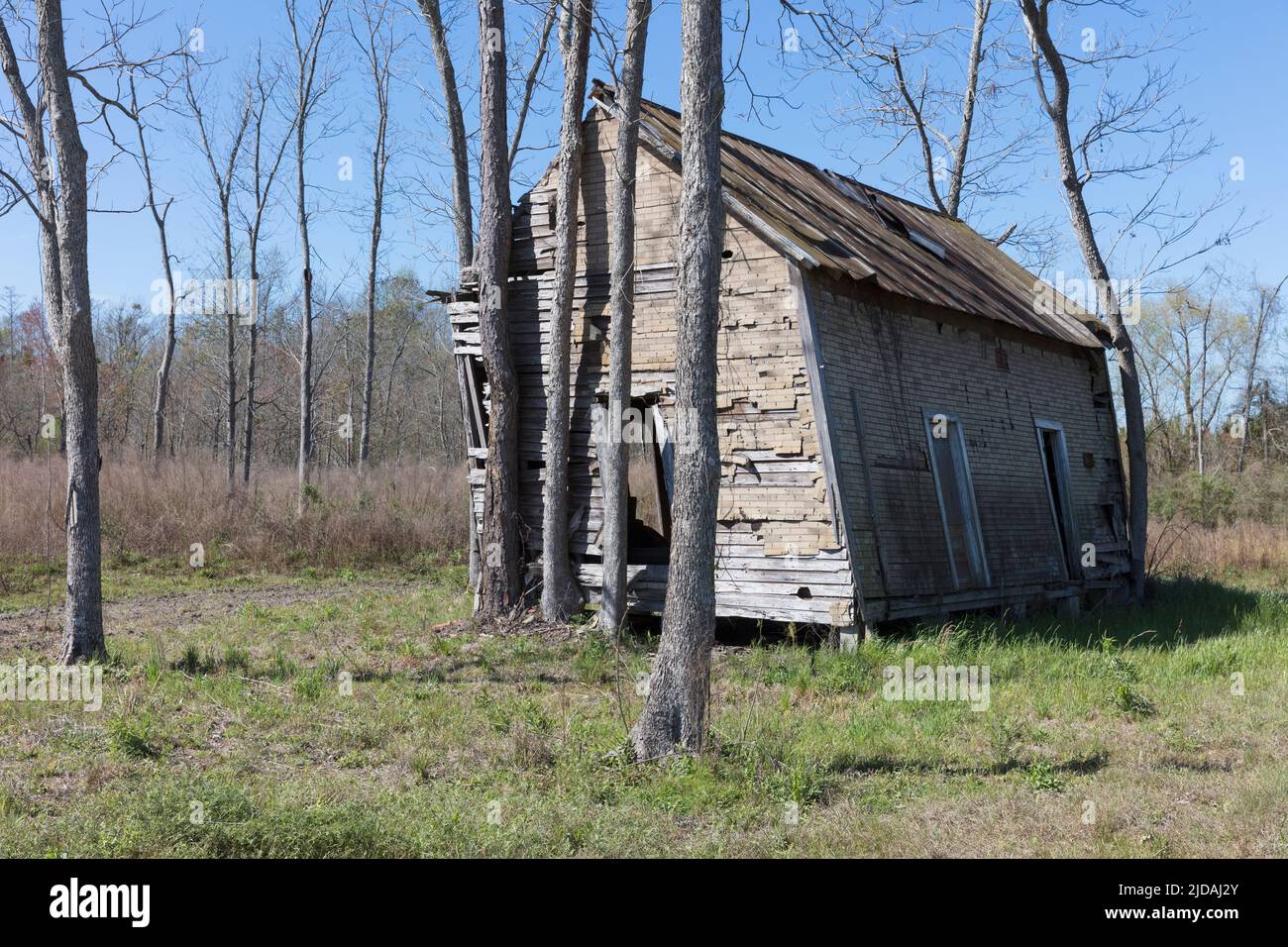 Abandoned homestead, a small log cabin, a building leaning to the side. Stock Photo