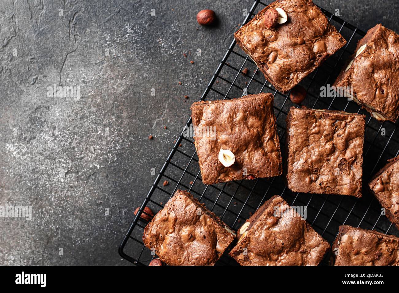 Chocolate brownies with nuts on baking rack on dark background, top