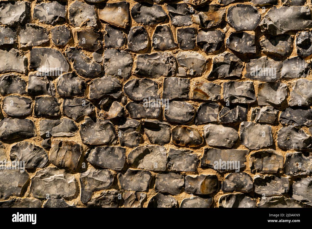View of a big wall made of flint stones, building material in architecture used in UK. Flint is the hardest of building stones, used by the Romans for Stock Photo
