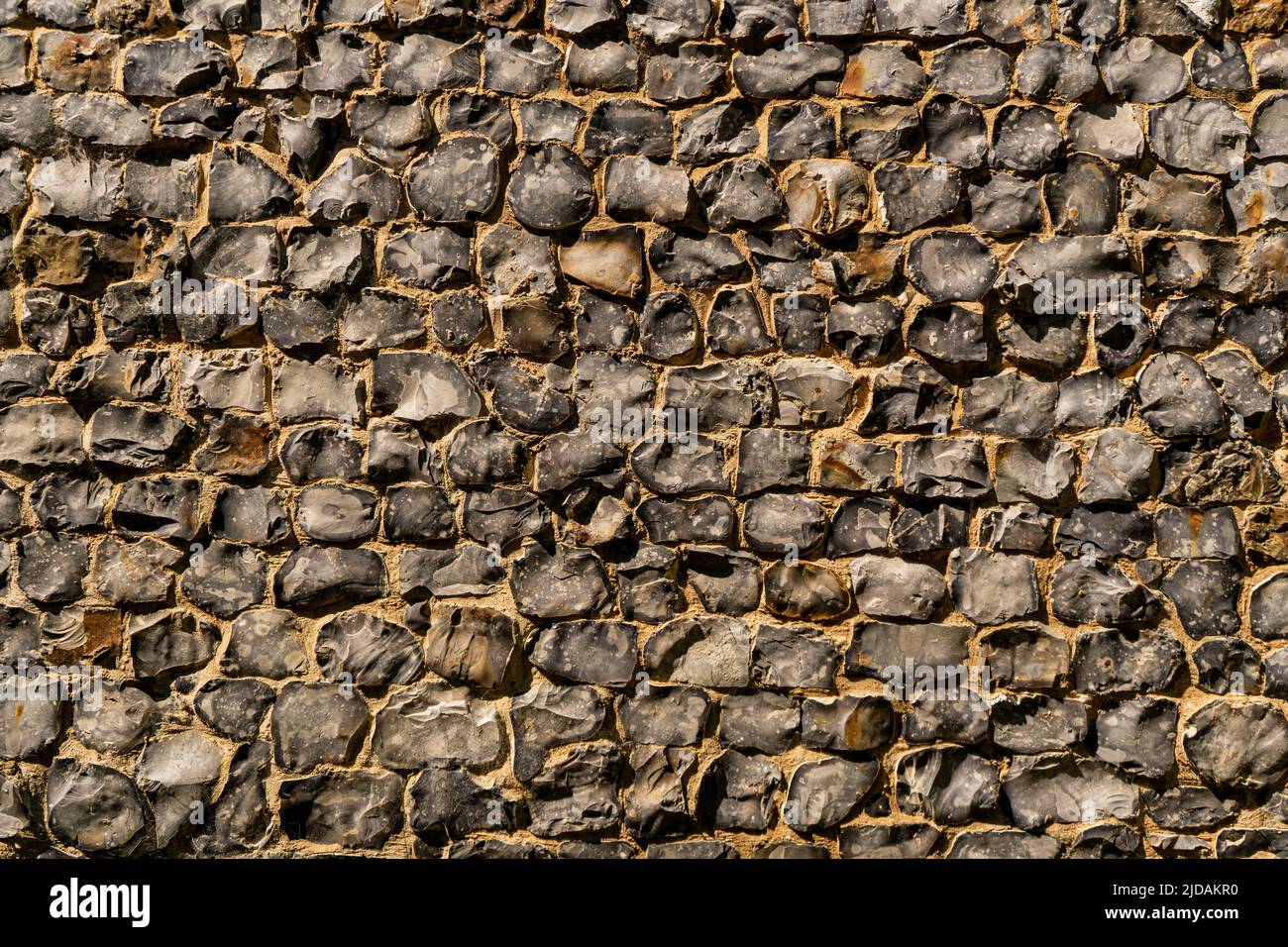 View of a big wall made of flint stones, building material in architecture used in UK. Flint is the hardest of building stones, used by the Romans for Stock Photo