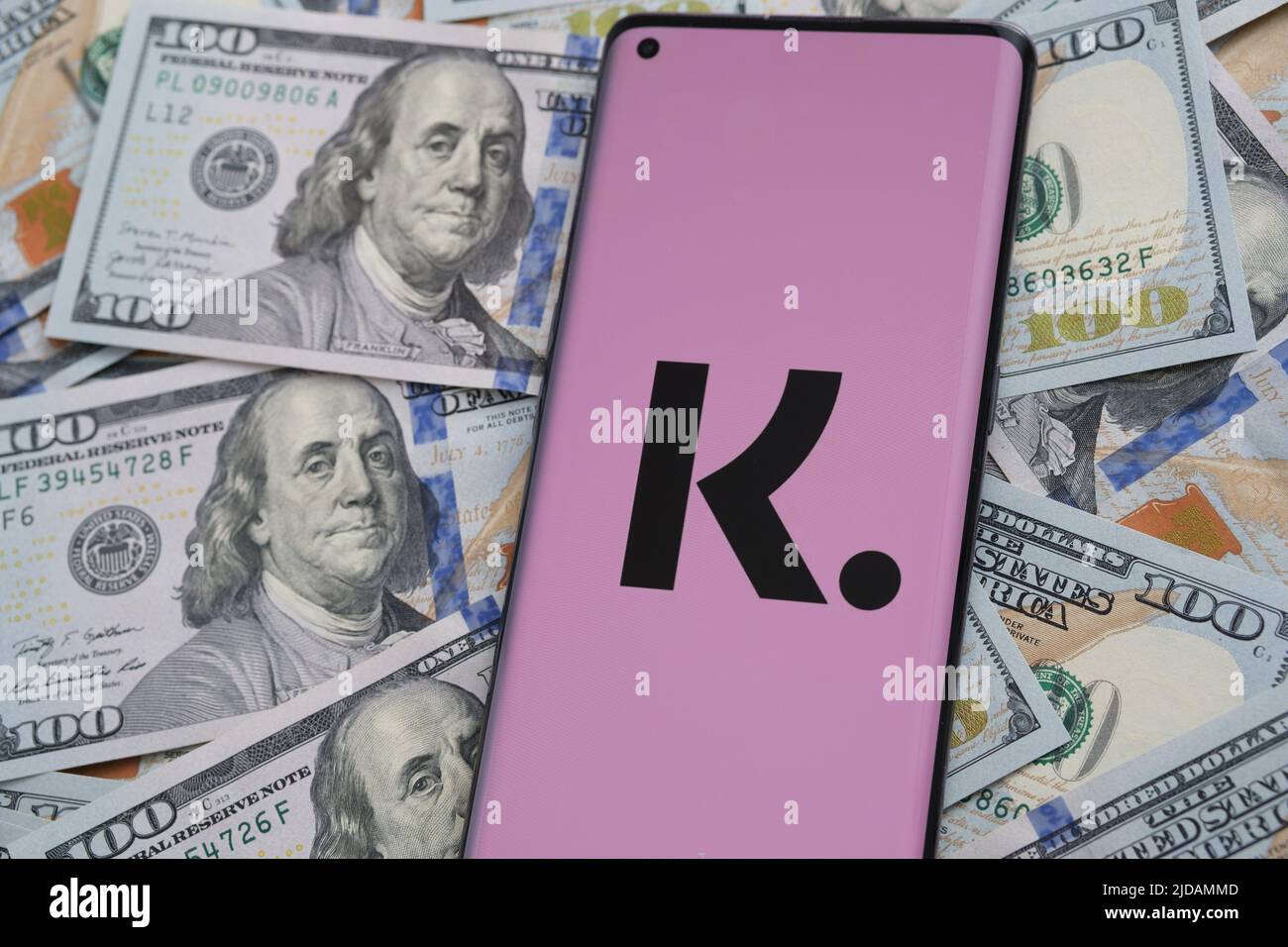 Klarna app logo seen on the screen of smartphone placed on dollar bills. Concept for credit app. Stafford, United Kingdom, June 19 2022 Stock Photo
