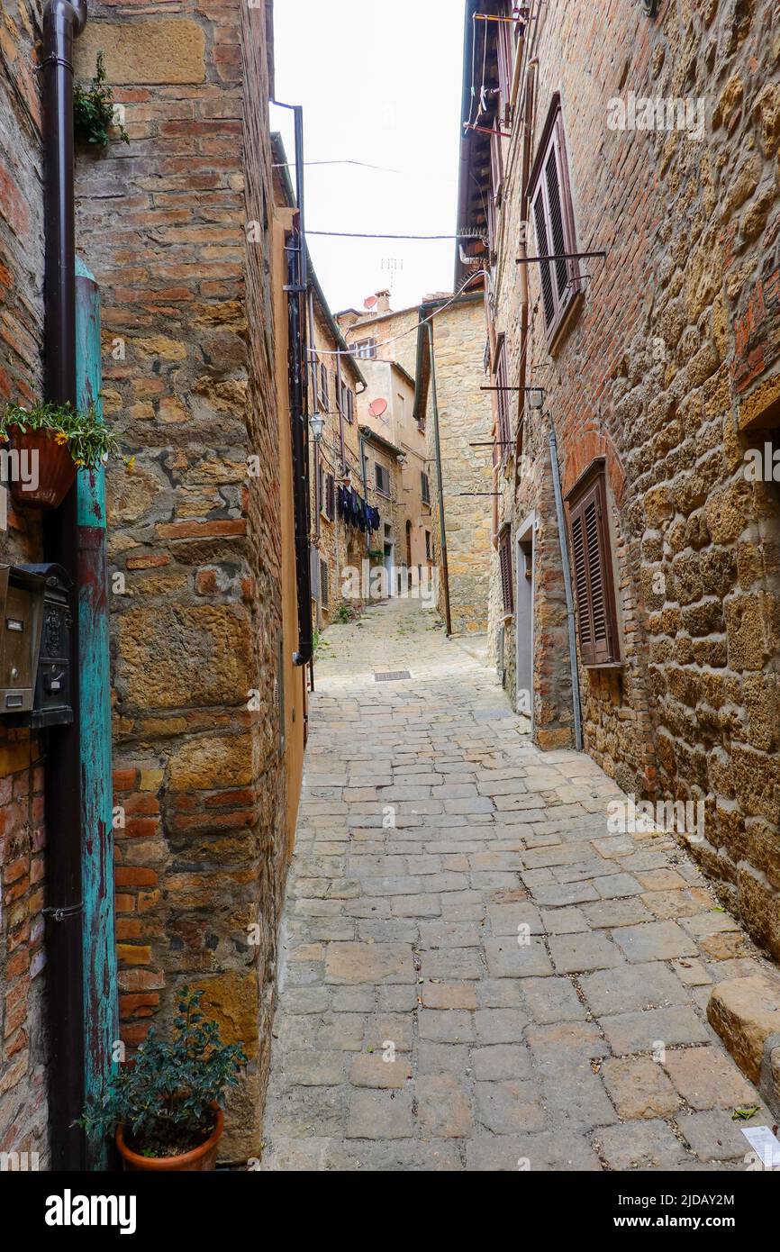 Very narrow pedestrian street winding it’s way through the walled town of Volterra in Tuscany, Italy. Stock Photo