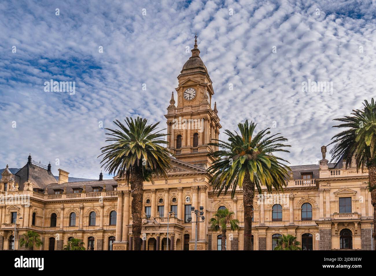 Palm trees in front of the facade of the Cape Town City Hall against a cloudy blue sky; Cape Town, Western Cape, South Africa Stock Photo