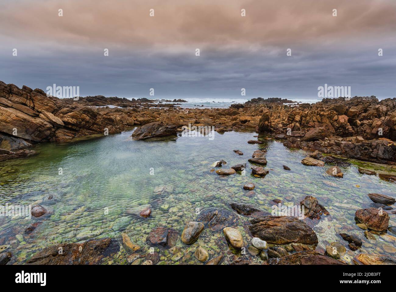 Rocky shore at Cape Agulhas, the Southern Most Point of the Continent of Africa and the maritime border of the Indian and Atlantic Oceans in Agulha... Stock Photo