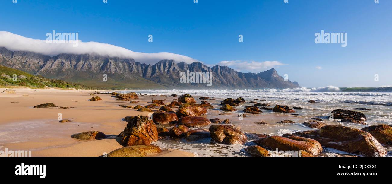 Rocky beach along the Atlantic Ocean at Kogel Bay with the Kogelberg Mountains in the background; Kogel Bay, Western Cape, South Africa Stock Photo