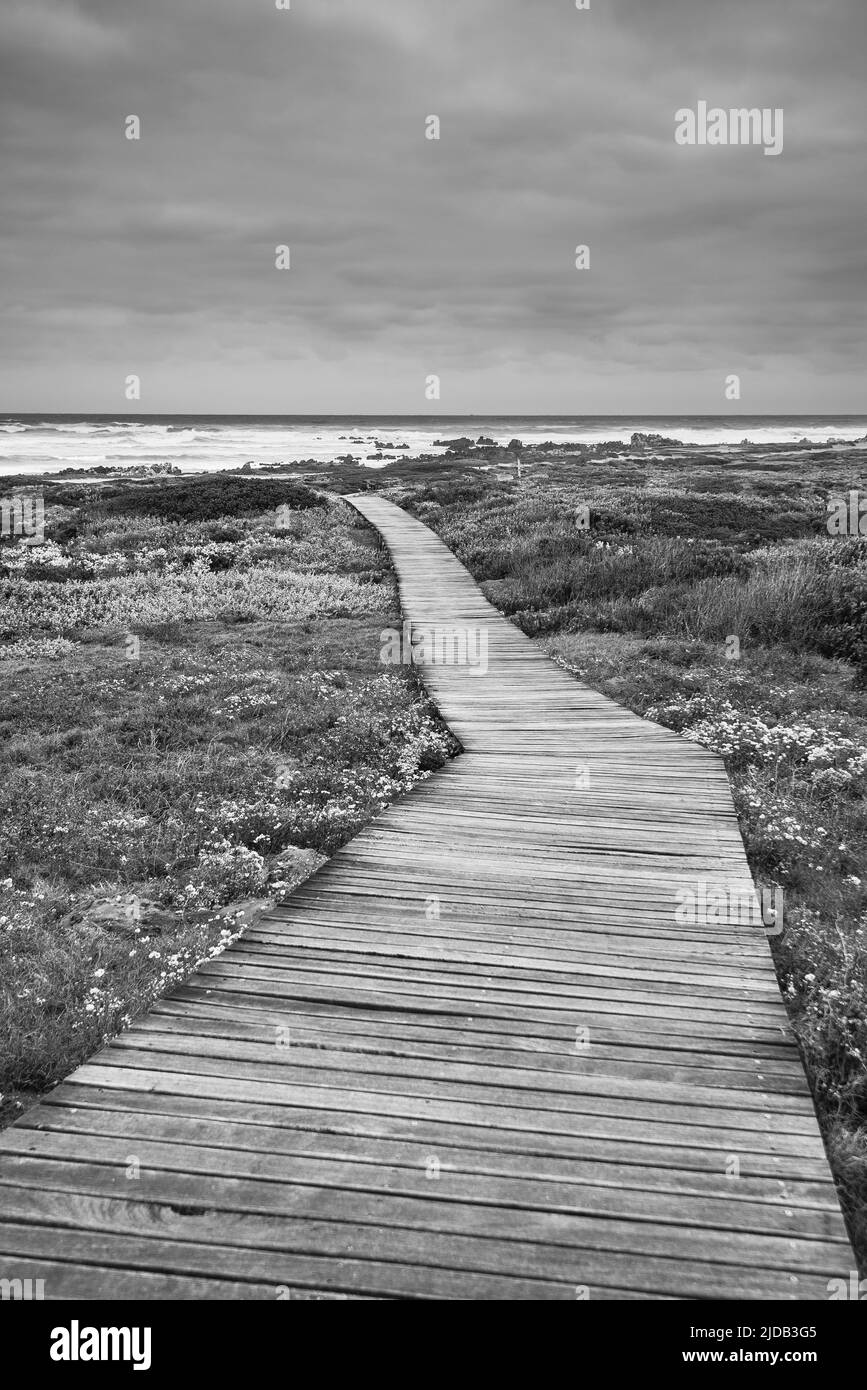 Wooden boardwalk across the moorland leading to the rocky shoreline at Cape Agulhas, the Southern Most Point of the Continent of Africa and the mar... Stock Photo