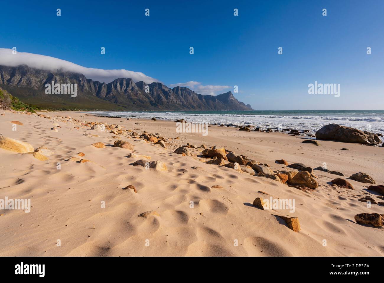 Sandy beach along the Atlantic Ocean at Kogel Bay with the Kogelberg Mountains in the background; Kogel Bay, Western Cape, South Africa Stock Photo