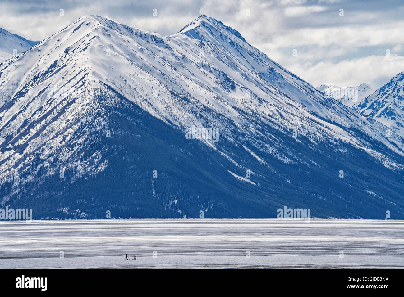 Two people walking with their dog on the frozen Bennett Lake during ...