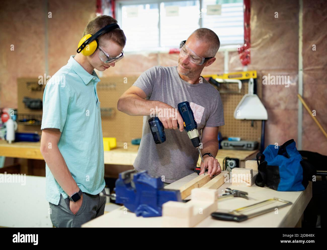 Young man doing woodworking in his basement while his father looks on