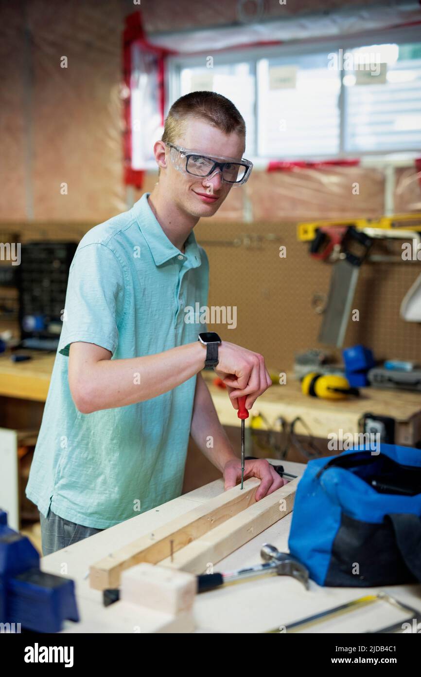 Young man doing woodworking in his basement; Edmonton, Alberta, Canada Stock Photo
