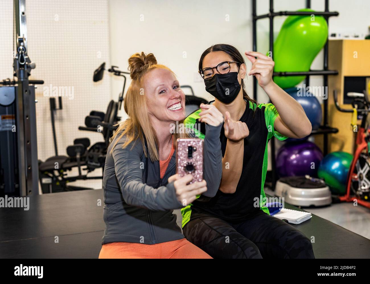 A paraplegic woman and trainer celebrating the day's accomplishment by posting on social media while clicking their fingers: Edmonton, Alberta, Canada Stock Photo