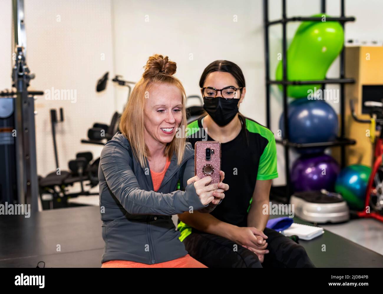 A paraplegic woman and trainer celebrating the day's accomplishment by posting on social media: Edmonton, Alberta, Canada Stock Photo